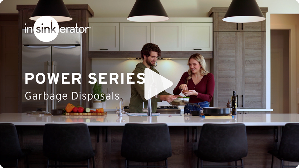 InSinkErator Power Series - a man holding a container and a woman adding seasoning while smiling